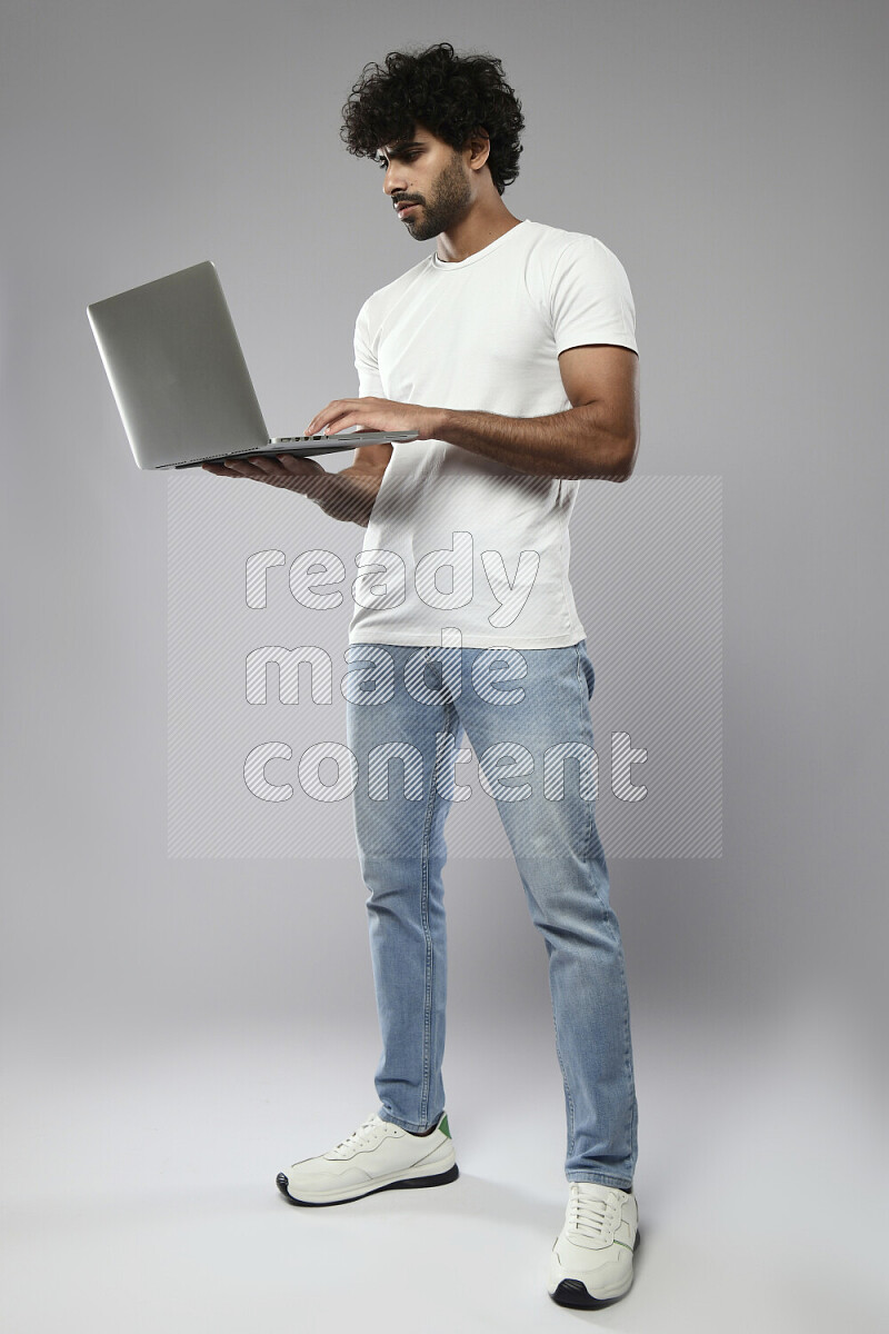 A man wearing casual standing and working on a laptop on white background