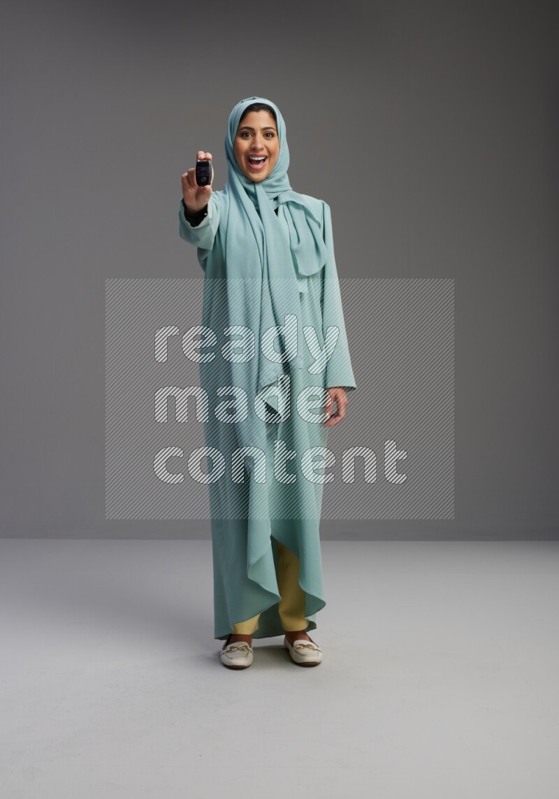 Saudi Woman wearing Abaya standing holding car key on Gray background