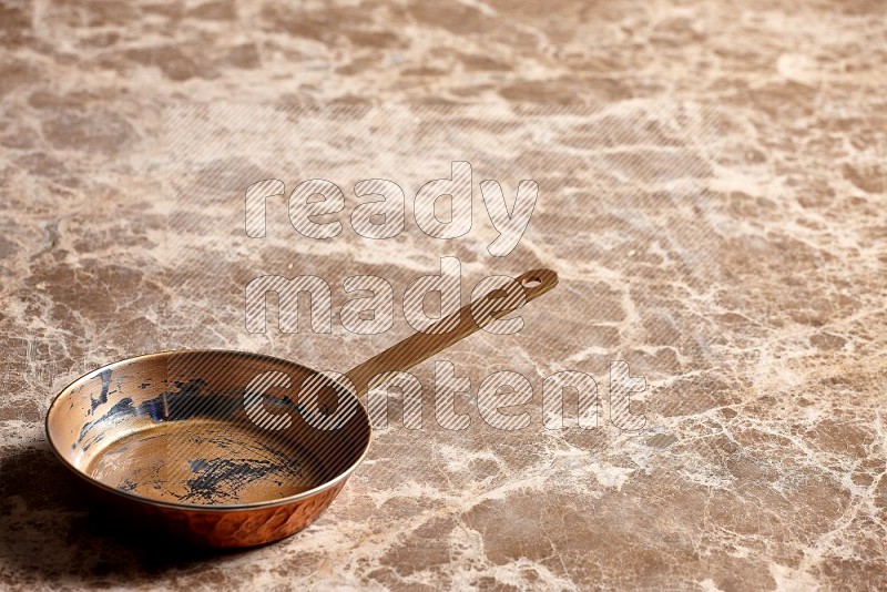 Small Copper Pan on Beige Marble Flooring, 45 degrees