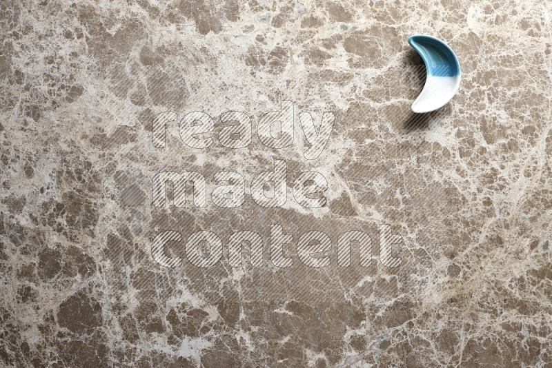 A pottery crescent plate on beige marble background