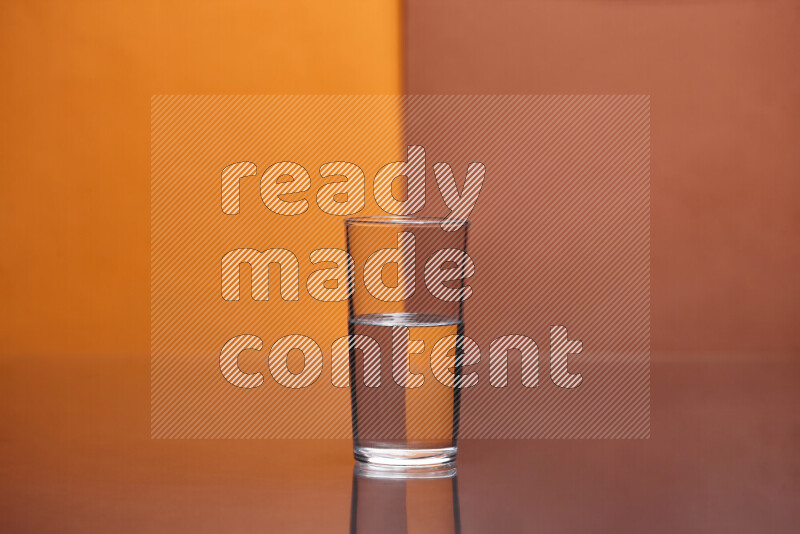 The image features a clear glassware filled with water, set against orange and dark orange background