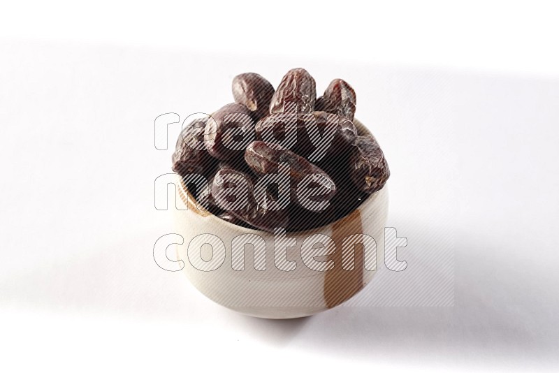 Dates in a beige pottery bowl on white background