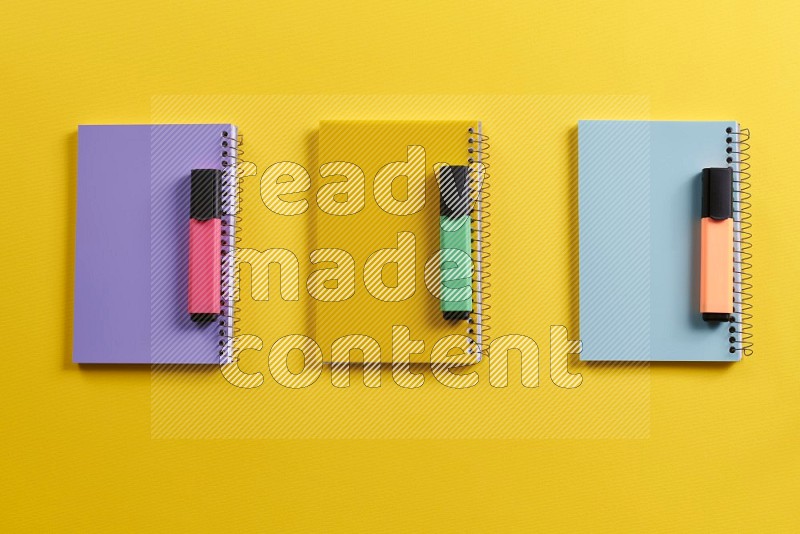 Multicolored notebooks with school supplies on yellow background (Back to school)