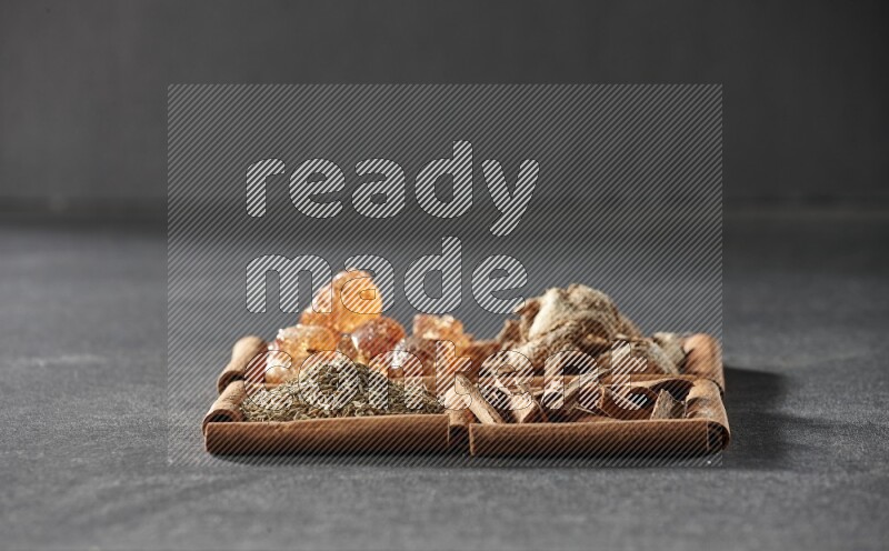 4 squares of cinnamon sticks full of gum arabic, dried ginger, cinnamon and cumin on black flooring