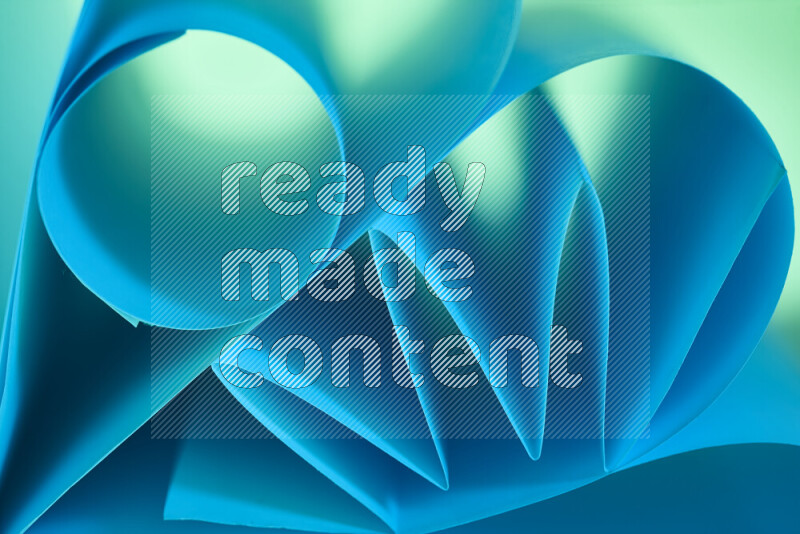 عرض فني لطيات الورق تخلق مزيج من الأشكال الهندسية، مضاءة بإضاءة ناعمة بدرجات اللون الأخضر والأزرق