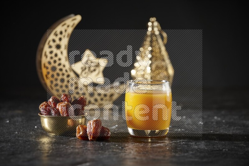 Dates in a metal bowl with qamar el din beside golden lanterns in a dark setup