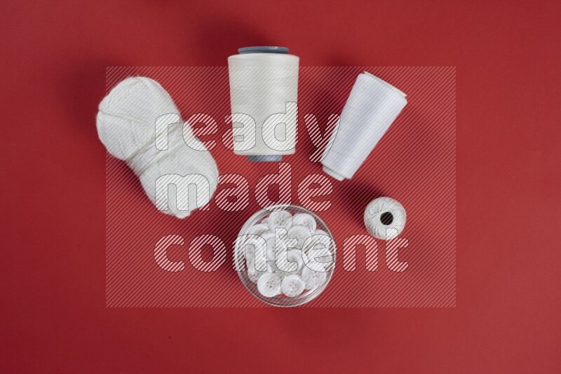 A white collection of sewing and tailoring tools arranged on a red background