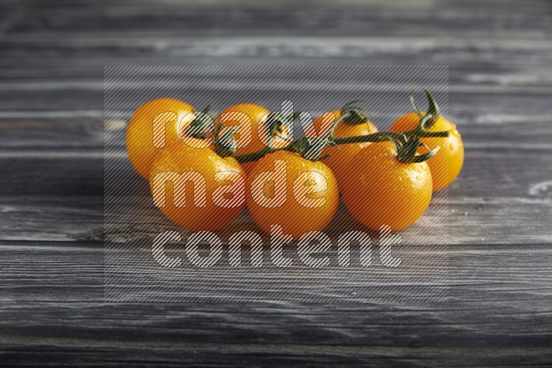 Yellow cherry tomato vein on a textured grey wooden background 45 degree