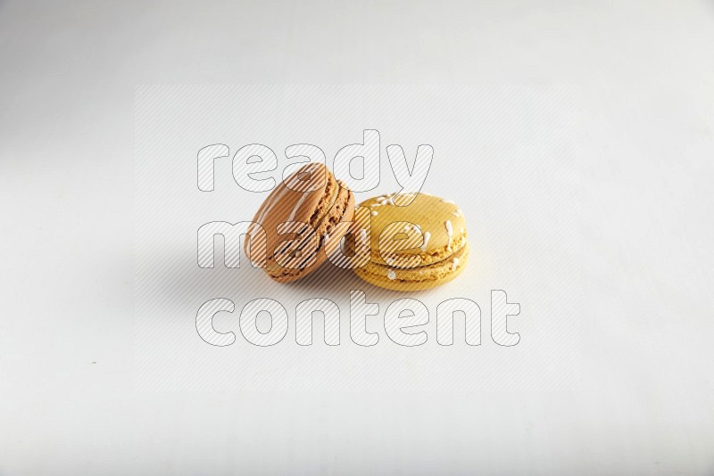 45º Shot of of two assorted Brown Irish Cream, and Yellow Piña Colada macarons on white background