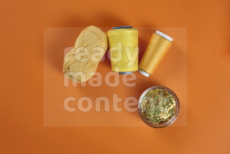 Yellow sewing supplies on orange background