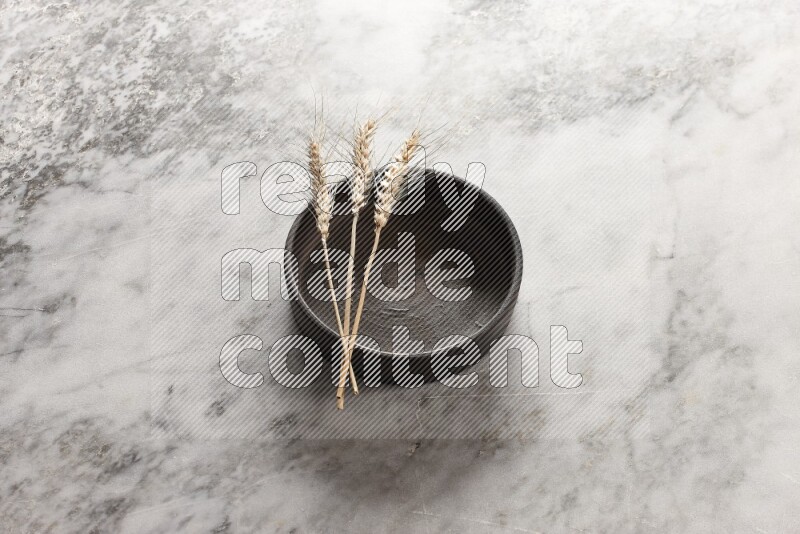 Wheat stalks on Black Pottery Oven Plate on grey marble flooring, 45 degree angel