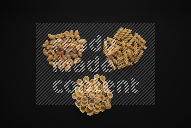 Different pasta types in bunches on black background