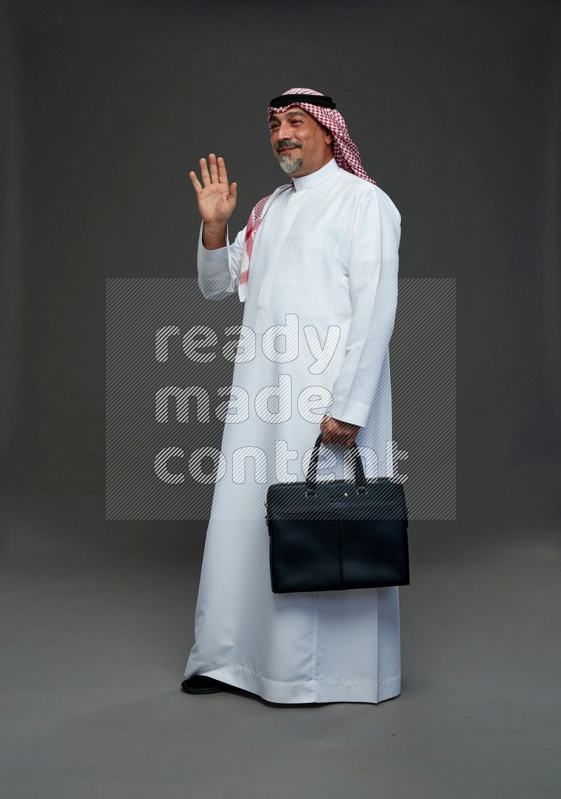 Saudi man with shomag Standing holding bag on gray background