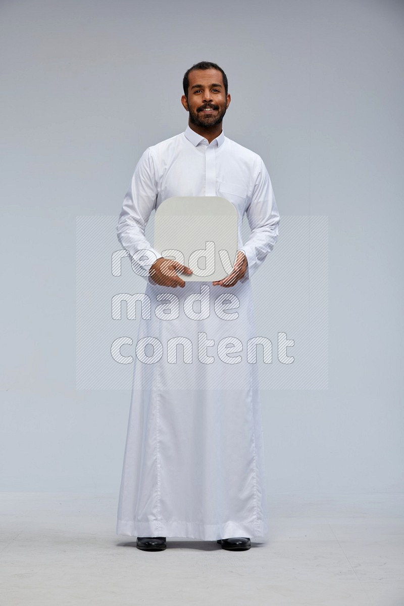 Saudi man wearing Thob standing holding social media sign on Gray background