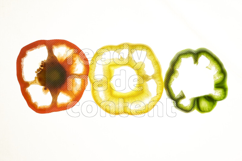 Colored bell pepper slices on illuminated white background