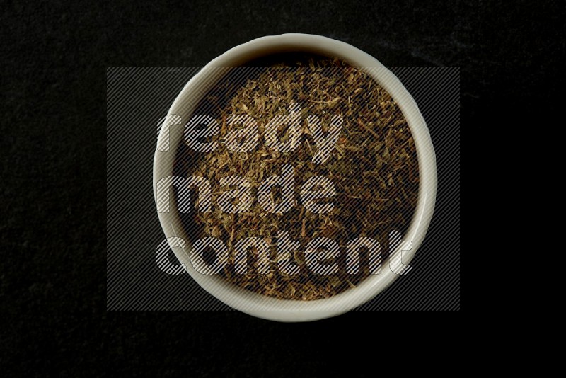 wooden round sauce bowl filled with herbs on grey textured countertop