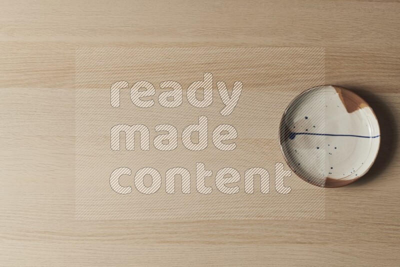 صحن فخاري متعدد الألوان على خلفية خشبية فاتحة