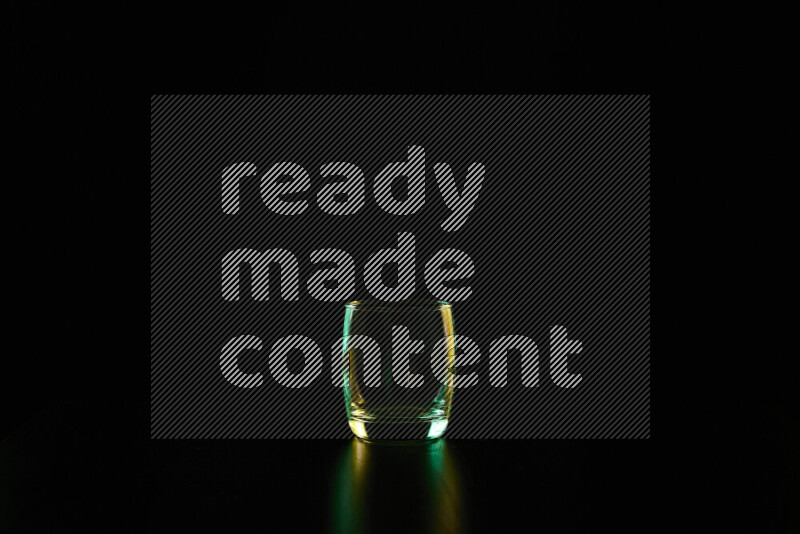 Glassware with rim light in green and yellow against black background