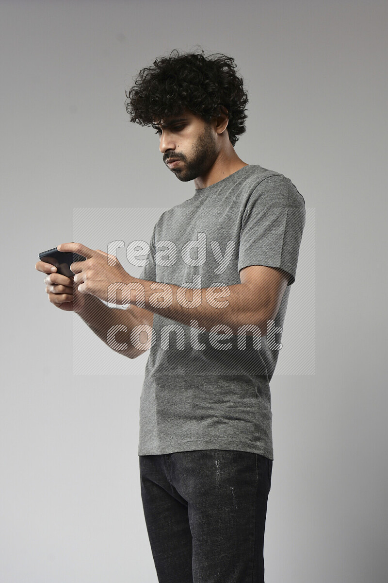 A man wearing casual standing and gaming on the phone on white background