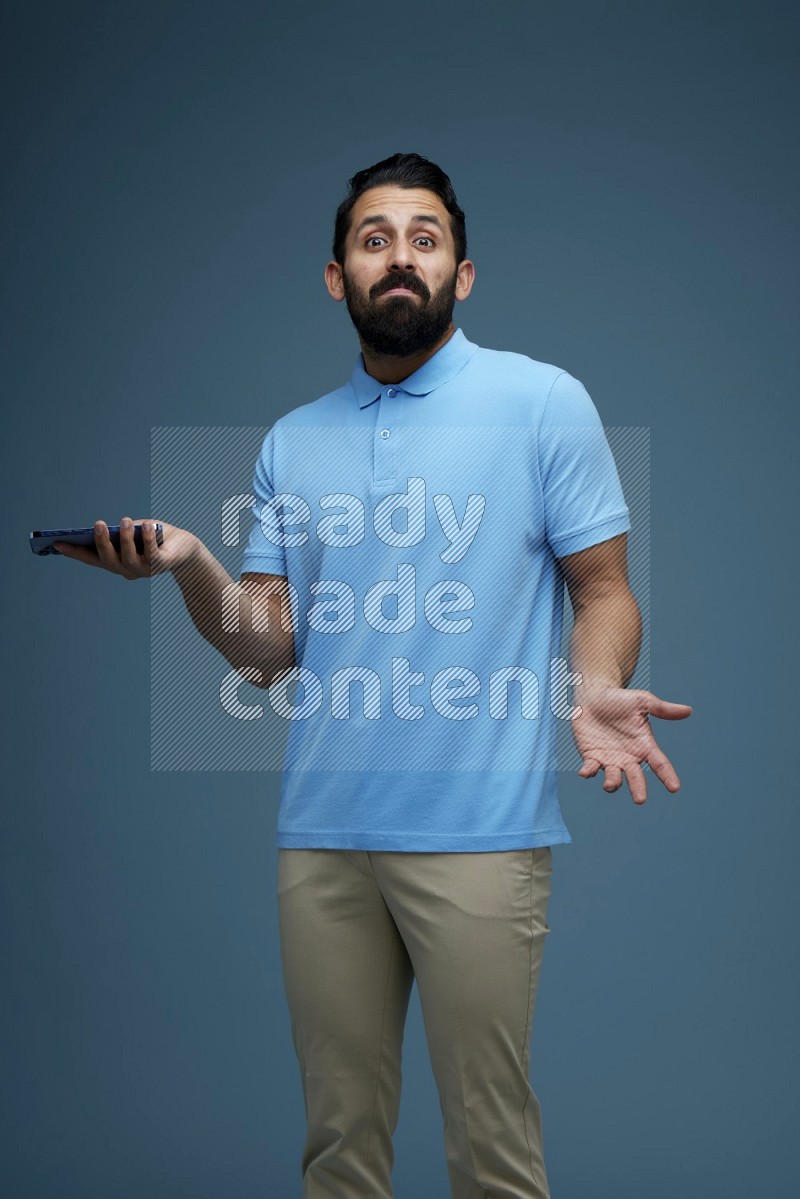 Man posing with a phone in a blue background wearing a Blue shirt
