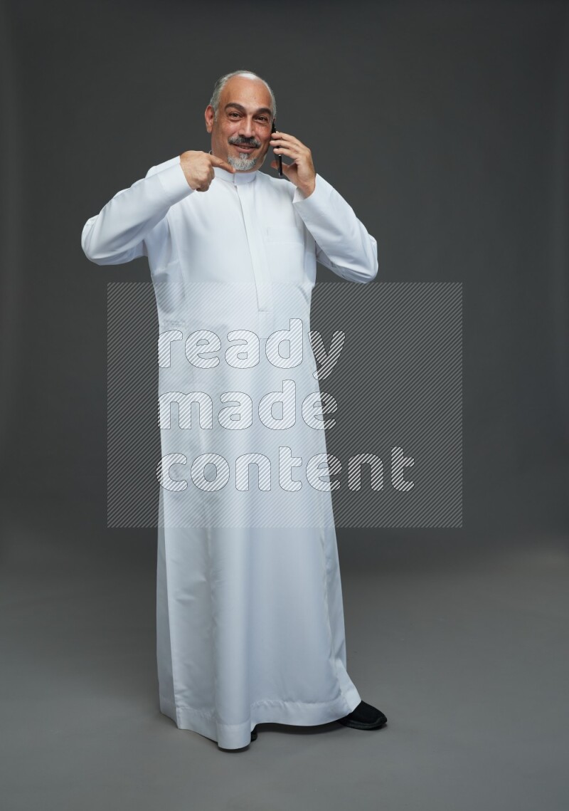 Saudi man without shomag Standing talking on phone on gray background