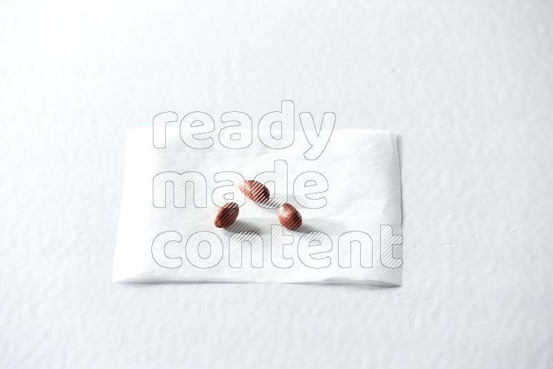 3 red skin peanuts on a piece of paper on a white background in different angles