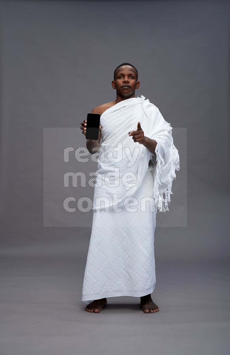 A man wearing Ehram Standing showing phone to camera on gray background