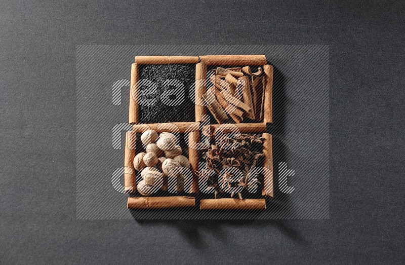 4 squares of cinnamon sticks full of black seeds, cinnamon, star anise and nutmegs on black flooring