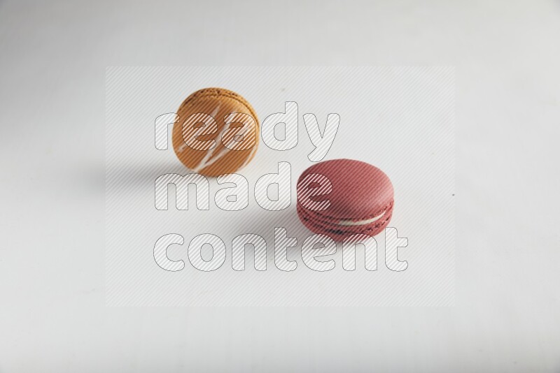 45º Shot of of two assorted Brown Irish Cream, and Red Velvet macarons on white background