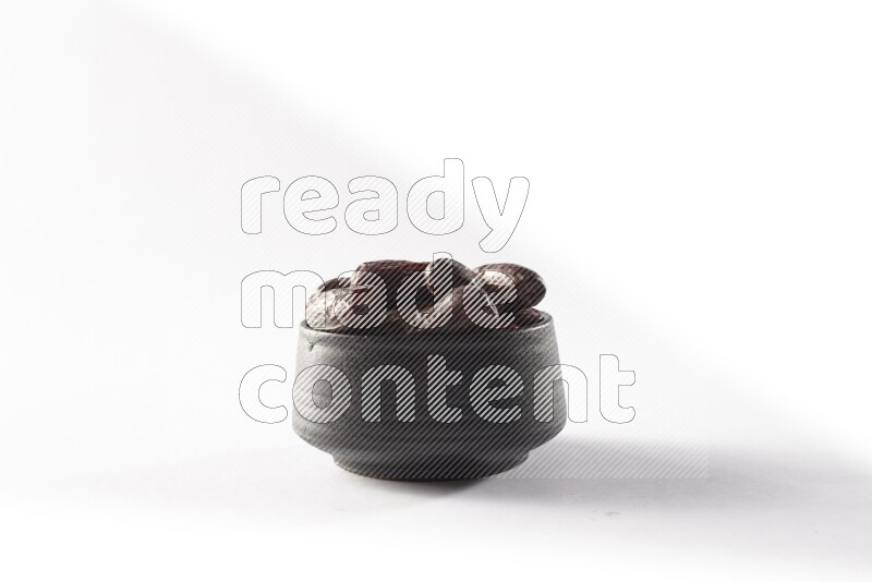 Dates in a black pottery bowl on white background