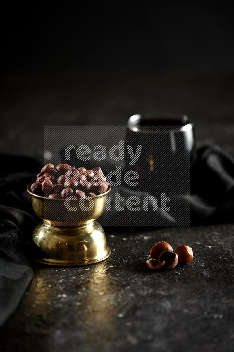 Nuts in a metal bowl with tamarind and a napkin in a dark setup