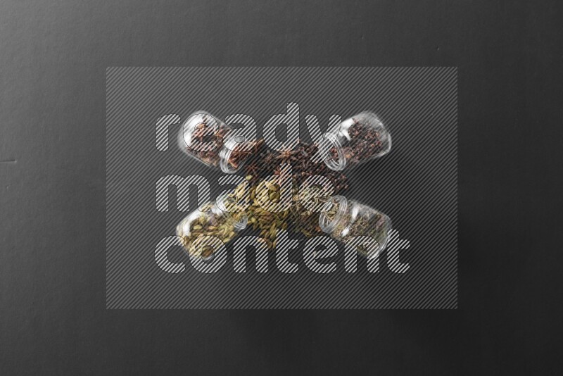 قرنفل وحبوب الهيل وريحان مجفف ويانسون نجمي في أوعية زجاجية علي خلفية سوداء