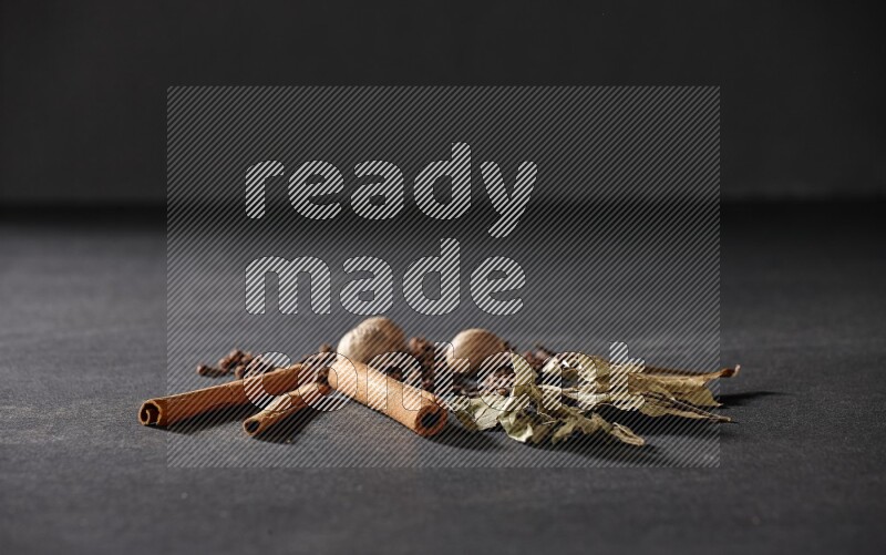 القرنفل والزنجبيل وورق الغار وأعواد القرفة على خلفية سوداء