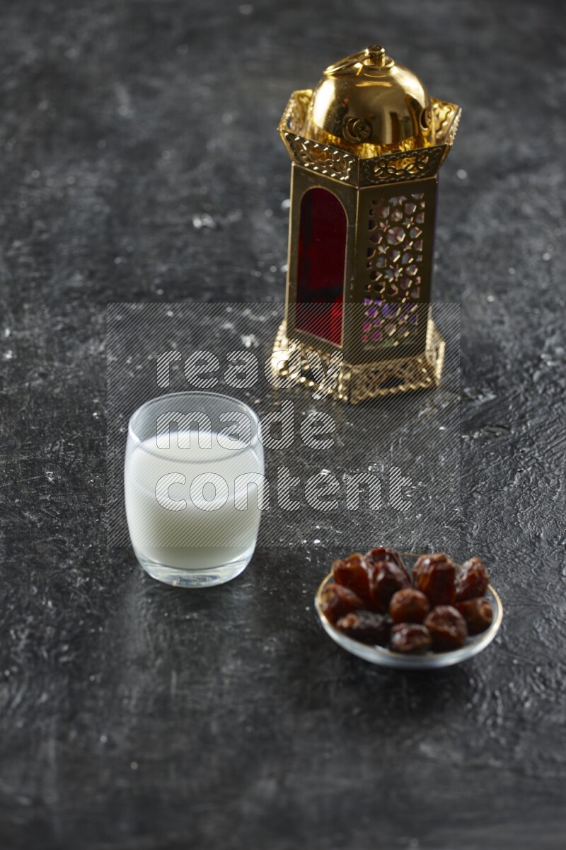 A golden lantern with different drinks, dates, nuts, prayer beads and quran on textured black background