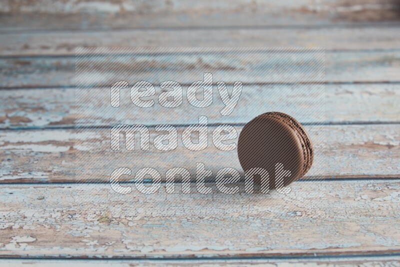 45º Shot of Brown Dark Chocolate macaron on light blue wooden background