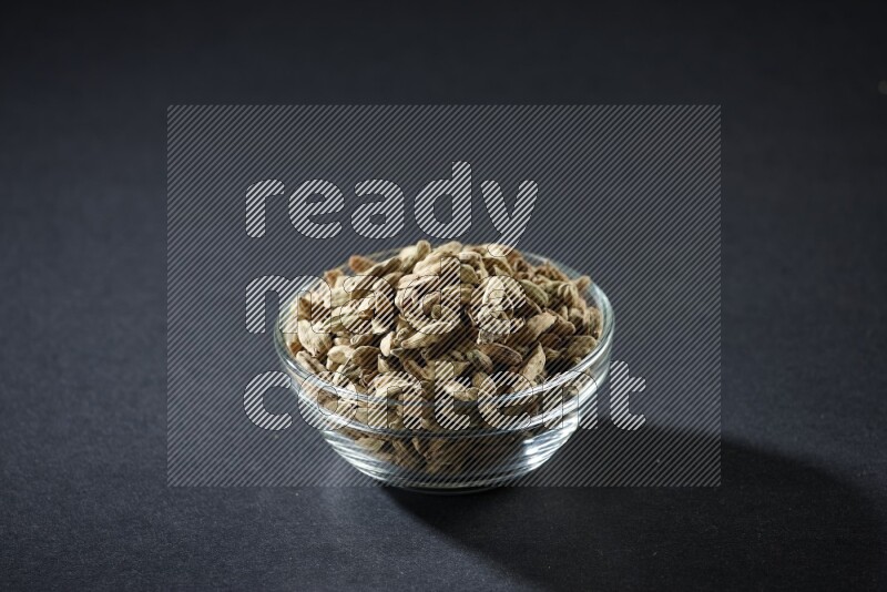 A glass bowl full of cardamom on black flooring