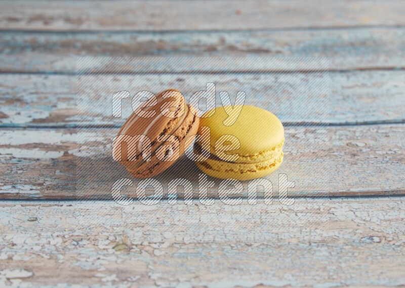 45º Shot of of two assorted Brown Irish Cream, and Yellow Lemon macarons on light blue background