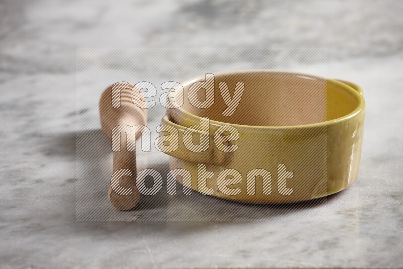 Multicolored pottery bowl with wooden honey dipper on the side on grey marble background