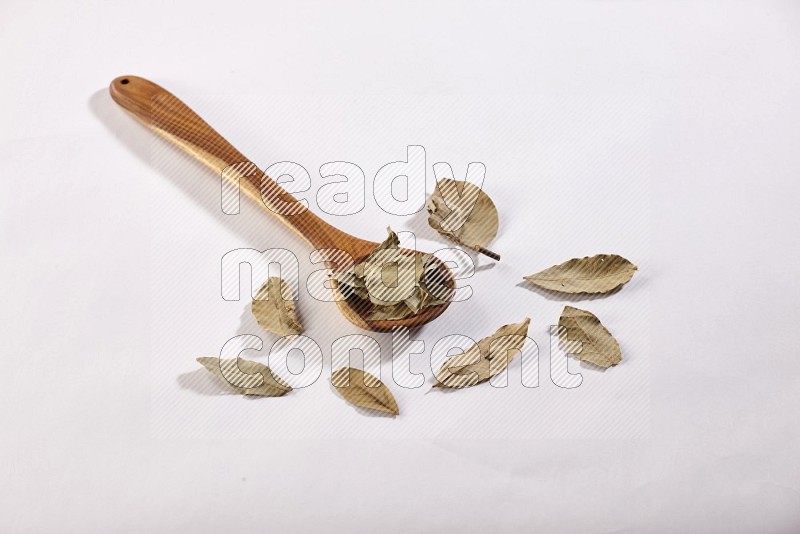 A wooden ladle filled with laurel bay on white flooring in different angles