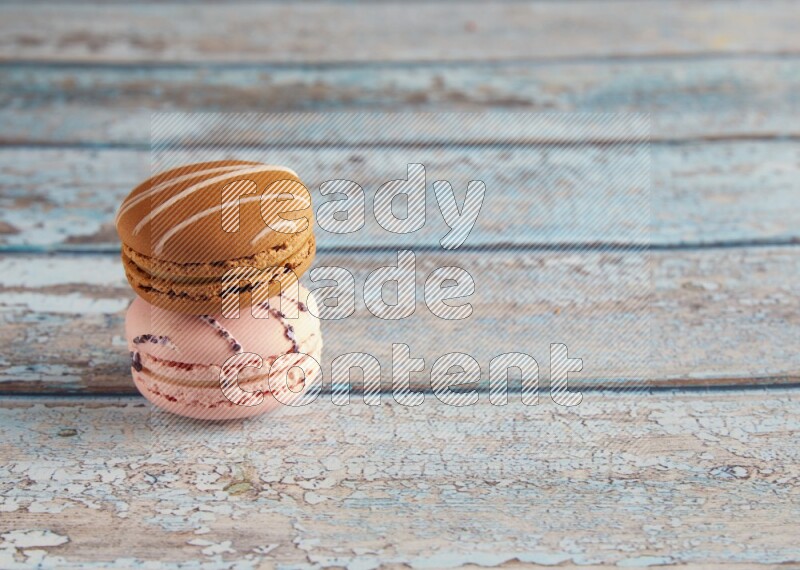 45º Shot of of two assorted Brown Irish Cream, and pink orange blossom  macarons on light blue background