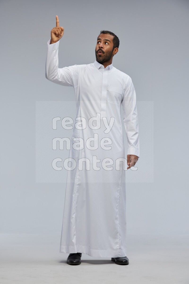 Saudi man Wearing Thob standing interacting with the camera on Gray background