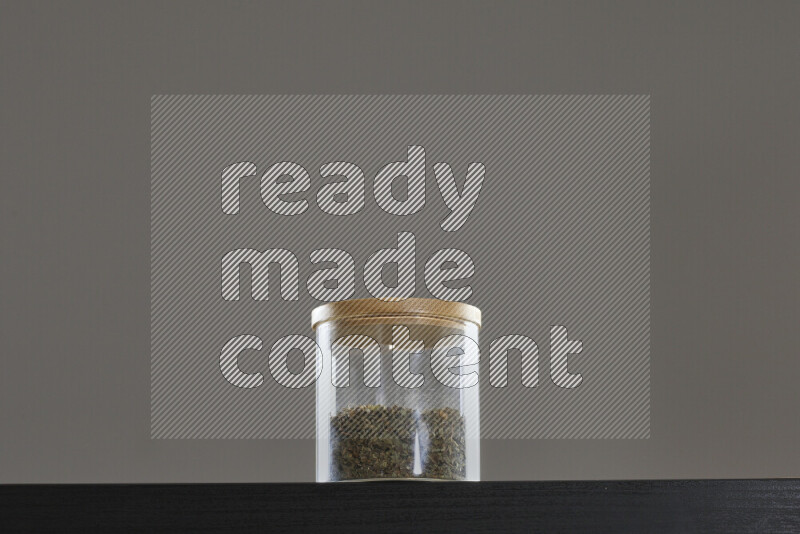 Dried basil in a glass jar on black background