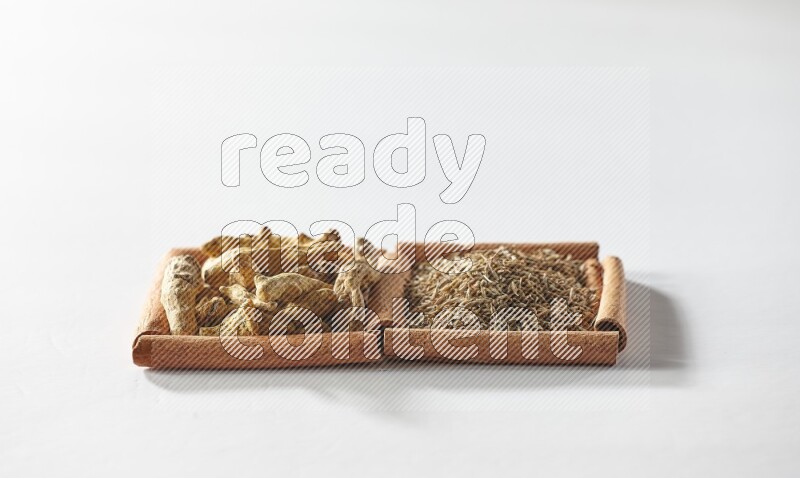 2 squares of cinnamon sticks full of cumin and turmeric fingers on white flooring