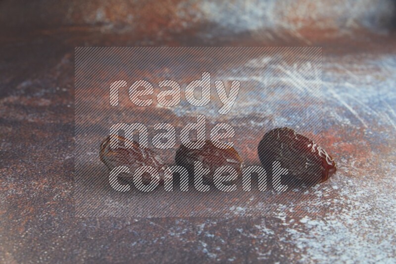 three madjoul dates on a rustic reddish background