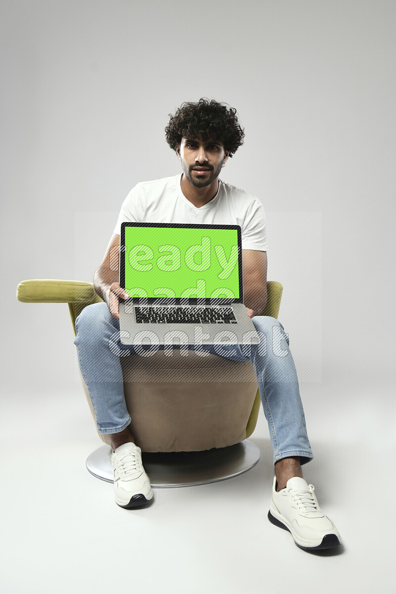 A man wearing casual sitting on a chair showing a laptop screen on white background