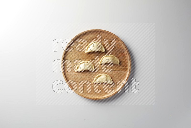 Four Sambosas on a wooden round plate on a white background