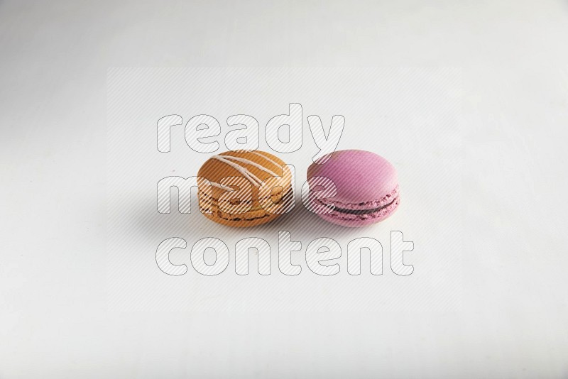 45º Shot of of two assorted Brown Irish Cream, and Purple Strawberry macarons on white background