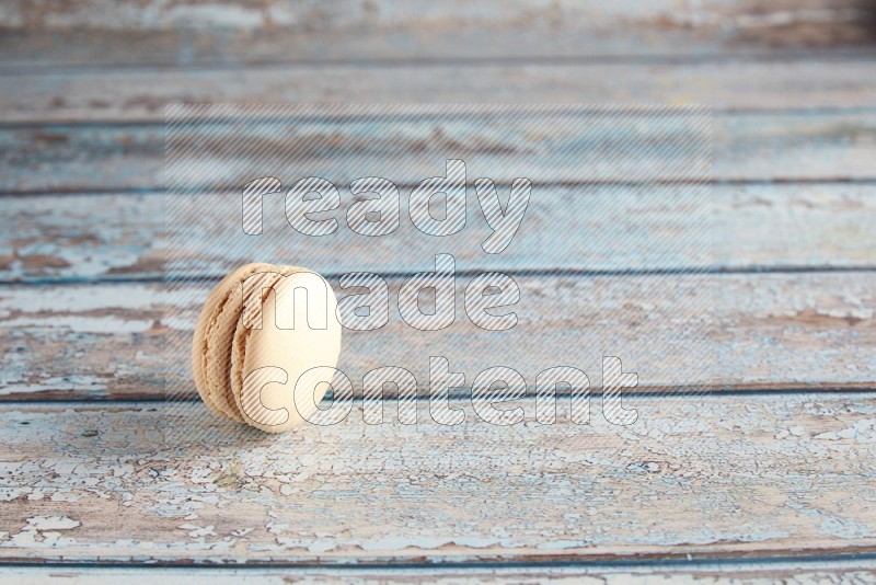 45º Shot of White Caramel fleur de sel macaron on light blue wooden background