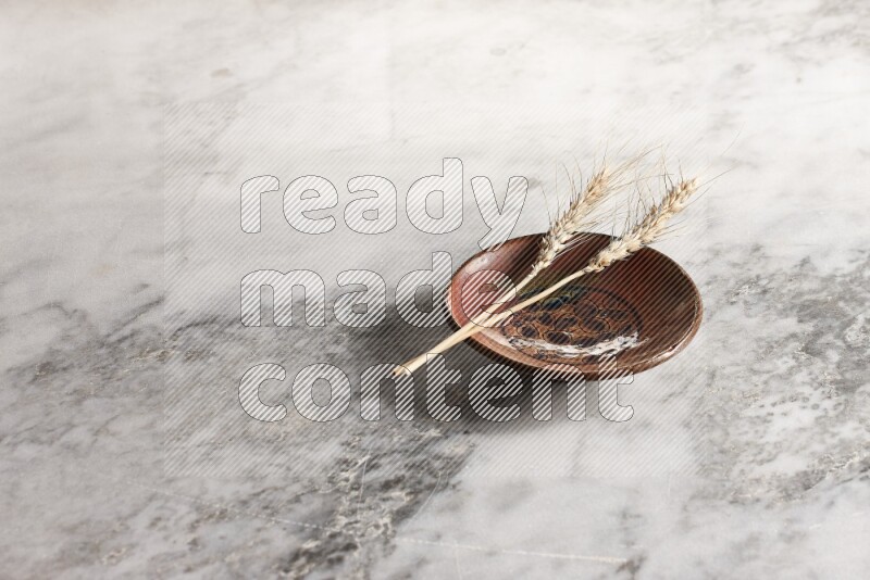 Wheat stalks on decorative pottery plate on grey marble background
