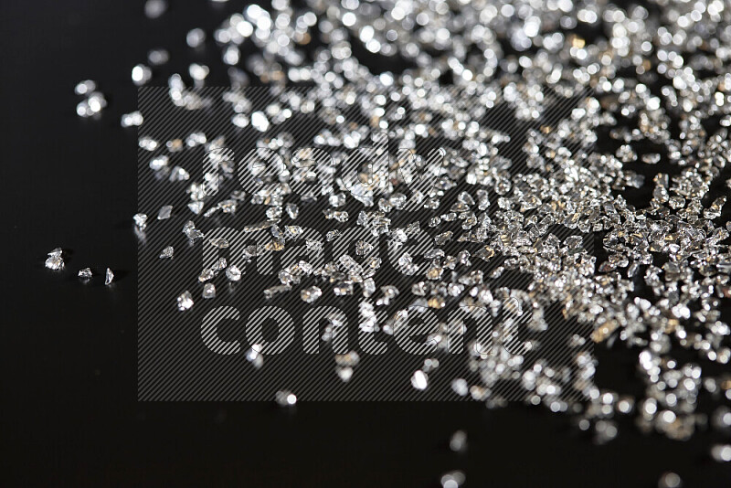 Silver shimmering fragments of glass scattered on a black background